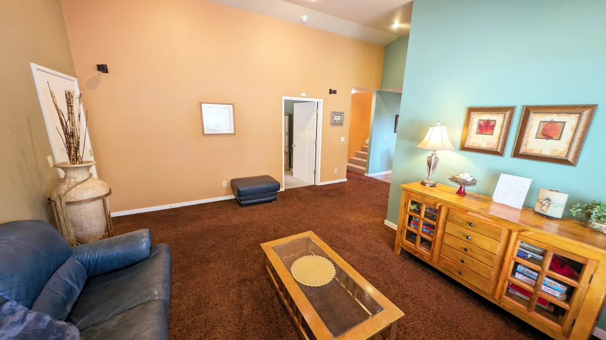 A cozy living room featuring a plush sofa, coffee table, subtle wall art, and a soft lamp glow. The mood is comfortable and welcoming, ideal for unwinding indoors with climate-controlled comfort—air conditioning in the summer or heating in the winter.