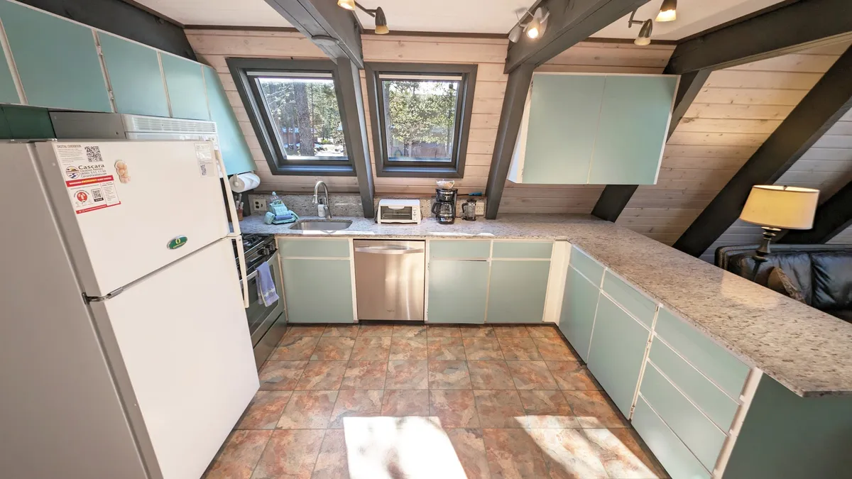 A bright, cheerful kitchen with a large countertop, modern appliances, and a window that lets in ample natural light. The space is set up for both cooking and socializing, supporting a lively, communal atmosphere.